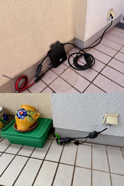Two photos showing an electrical setup on a tiled floor. In the top image, a black inverter sits on beige tiles near a wall corner, with various cables including red and black wires extending from it, and a power cord plugged into a wall outlet. In the bottom image, the inverter is inside a green plastic container with tidy cables extending from it, holding a decorative yellow ceramic cup with blue floral design.