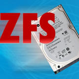 Bold red “ZFS” text overlaid on a tilted laptop hard disk drive against a bright blue background.