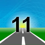 The number “11” stands large against a glowing horizon where a road disappears into a blue sky and green fields.