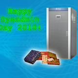 Green glowing “Happy Sysadmin Day 2010!” text beside a large Sun Microsystems server rack with wrapped gift boxes at its base.