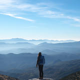 A person, standing on top of a hill, overlooking a vast landscape of hills.