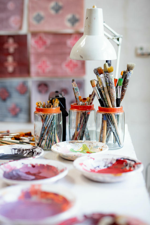 A table with brushes, colors, a lamp and creative background.