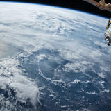 Earth from space, with a satellite in the top right corner.